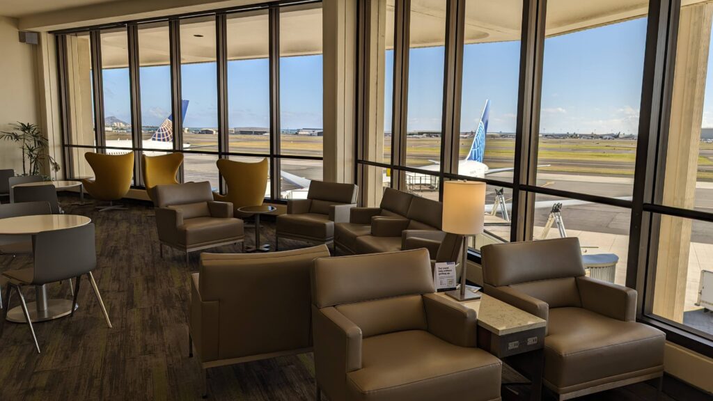 United Airlines Club Honolulu | Unique & Spacious Hawaii Calling a lounge area with chairs and tables and a lamp