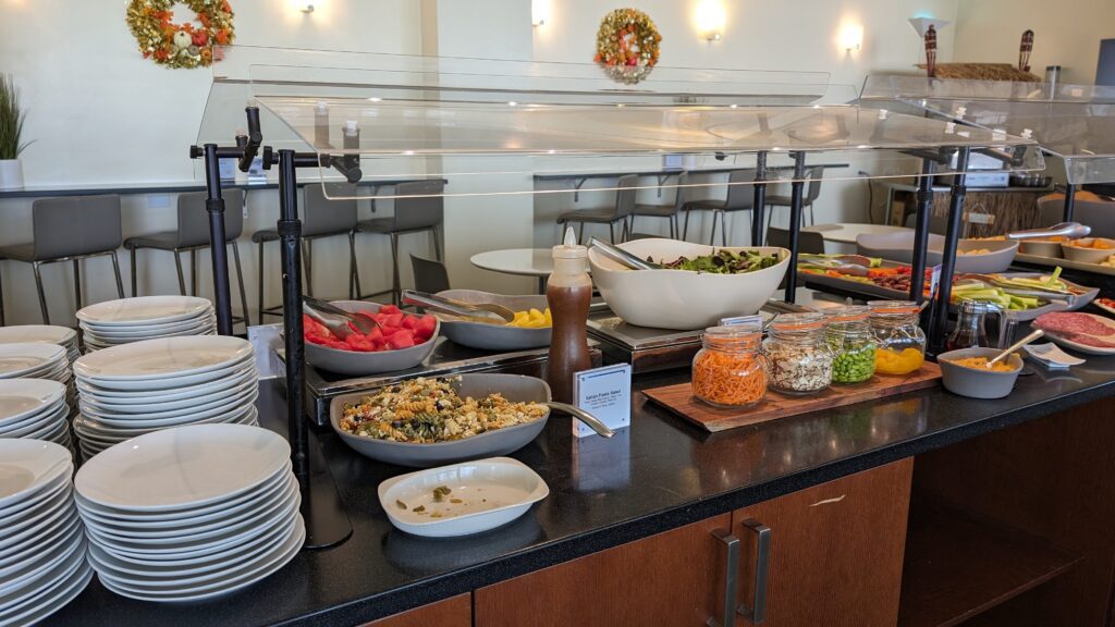 United Airlines Club Honolulu | Unique & Spacious Hawaii Calling a buffet with plates and bowls of food