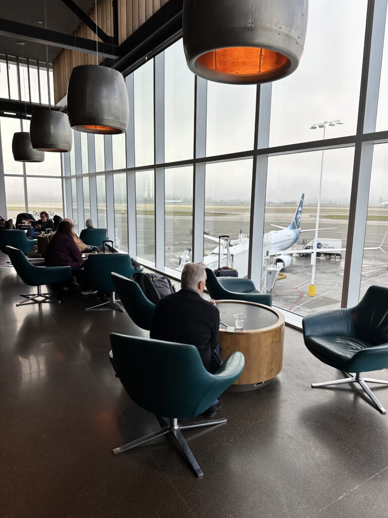 Review: Alaska Airlines Boeing 737 Max 9 First Class SEA-HNL Hawaii Calling people sitting in chairs in a room with large windows