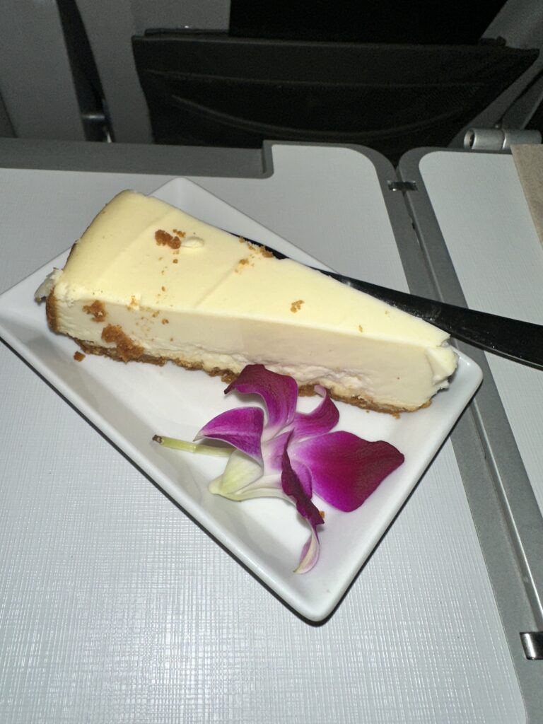 Review: Alaska Airlines Boeing 737 Max 9 First Class SEA-HNL Hawaii Calling a slice of cheesecake on a plate with a flower