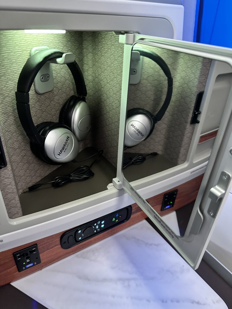 A First Class Experience on Hawaiian Airlines Boeing 787 Dreamliner | Leihōkū Suites | HNL-SFO Hawaii Calling a pair of headphones in a small cabinet