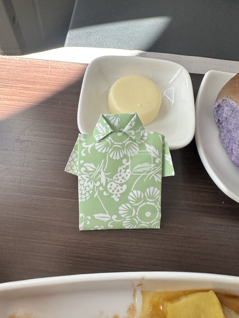 A First Class Experience on Hawaiian Airlines Boeing 787 Dreamliner | Leihōkū Suites | HNL-SFO Hawaii Calling a plate of food and a green shirt on a table