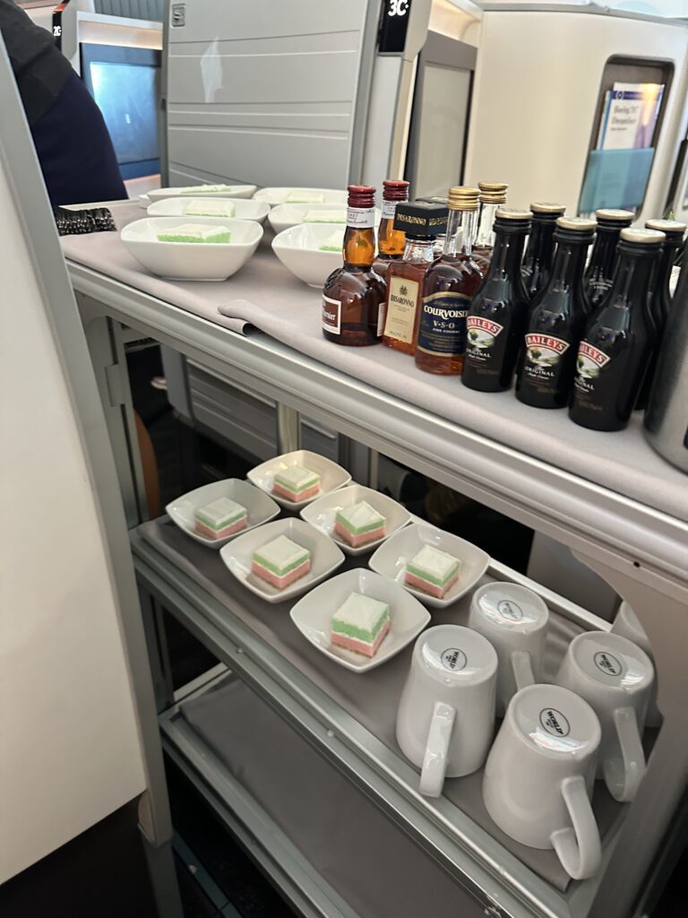 A First Class Experience on Hawaiian Airlines Boeing 787 Dreamliner | Leihōkū Suites | HNL-SFO Hawaii Calling a shelf with food and drinks on it