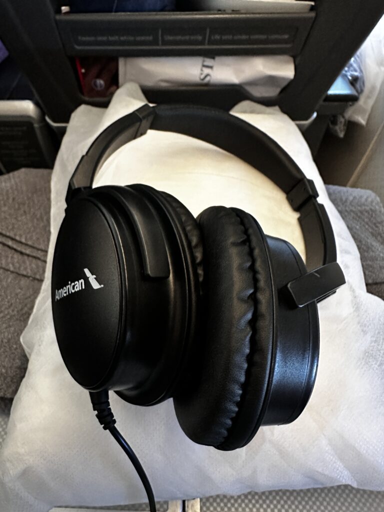 American Airlines DFW-HNL Premium Economy Review | Boeing 777 Hawaii Calling a black headphones on a white surface