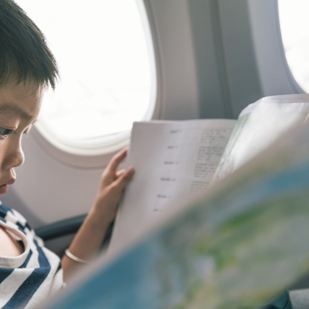 25 Fun & Creative Things To Do On A Long Flight To Hawai'i Hawaii Calling a boy reading a book on an airplane one of the best things to do on a long airplane flight