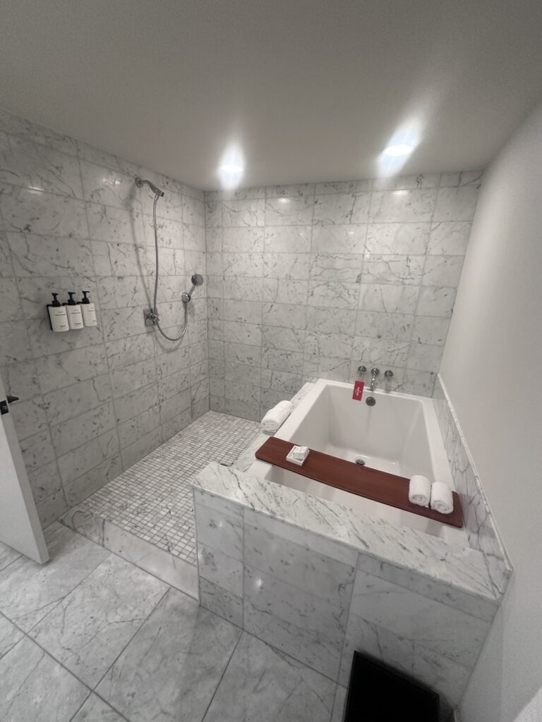 Ka La'i Waikiki Beach, A Hilton LXR Property | Review & Video Hawaii Calling a white and marble bathroom with a bathtub and shower