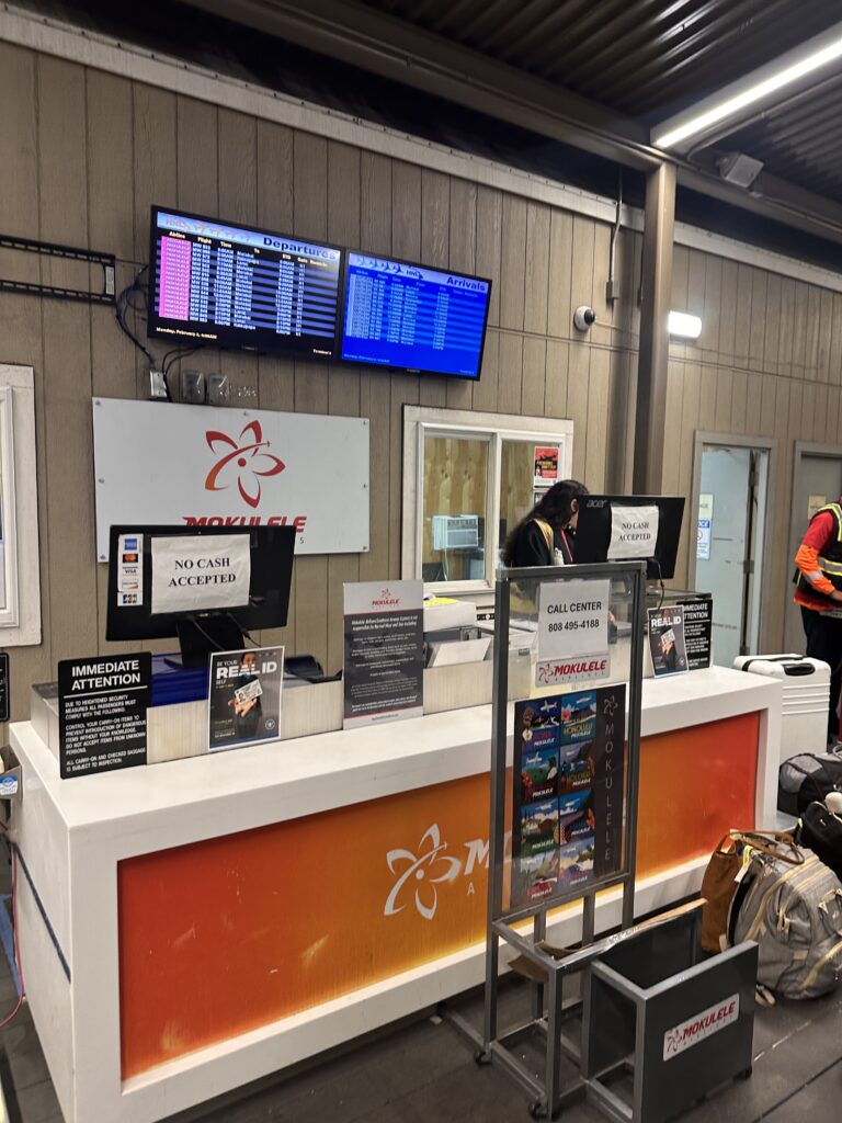 Mokulele Airlines Review: Honolulu (HNL) to Lāna‘i (LNY) | A Scenic Solo Flight Review Hawaii Calling a woman standing at a counter in a building