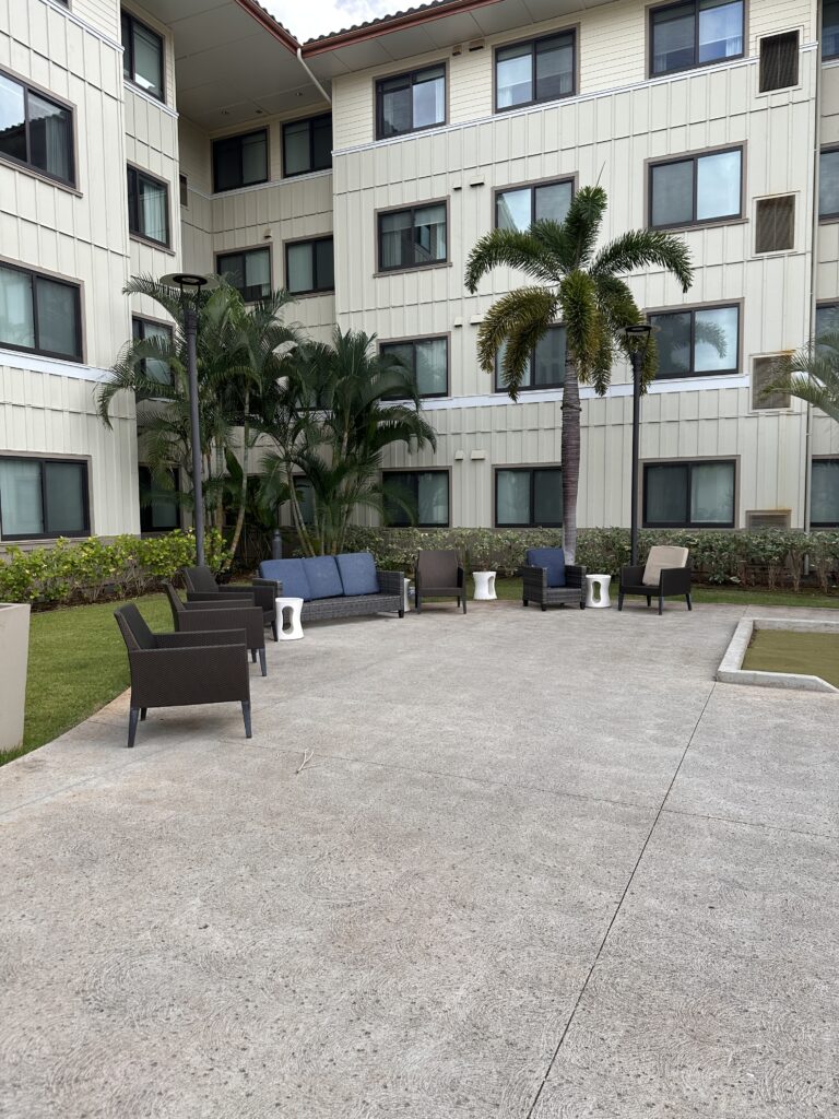 Residence Inn Oahu Kapolei: A Smart Option for Longer Stays on Oʻahu Hawaii Calling a patio with chairs and palm trees in front of a building