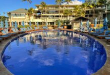 What Hotel Was The New Lilo & Stitch Movie Filmed? Inside the Iconic Kahala Hotel On Oahu a pool with lounge chairs and umbrellas in front of a building