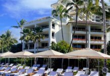 Where to Stay on O’ahu: Comparing Waikīkī, Ko Olina, and the North Shore a pool with umbrellas and lounge chairs in front of a building