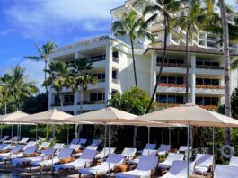 a pool with umbrellas and lounge chairs in front of a building