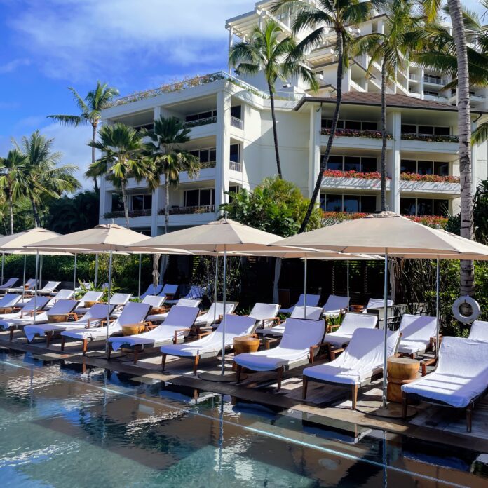 a pool with umbrellas and lounge chairs in front of a building