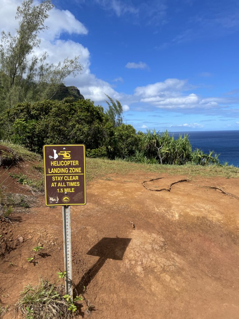 a sign on a dirt hill by the ocean