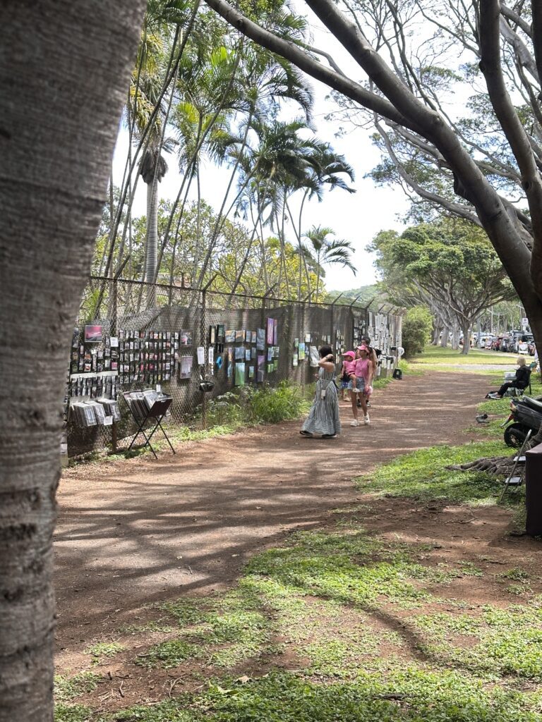 a group of people walking on a path with a fence and trees