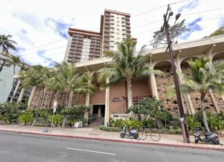 Queen Kapiolani Hotel Review: Retro Charm with Diamond Head Views front of the Queen Kapiolani Hotel in Waikiki with palm trees and a street