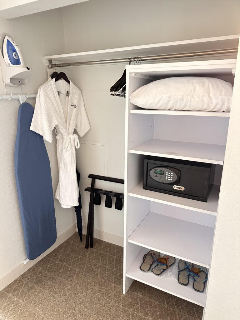 a white closet with a white robe and a ironed iron
