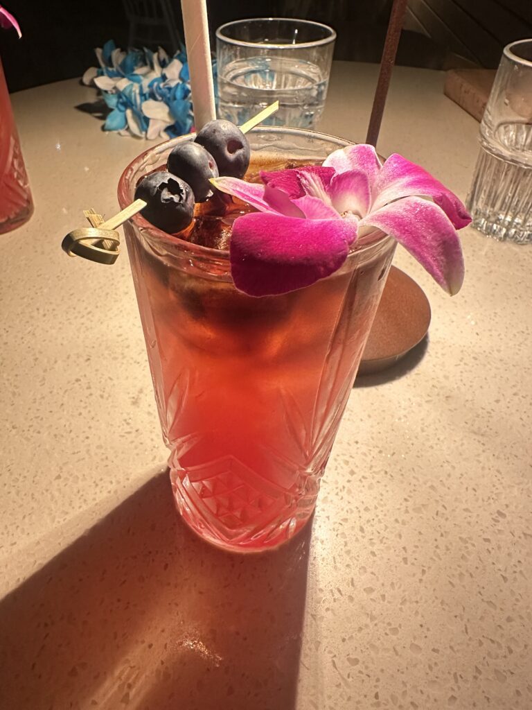 a glass with a drink and flowers