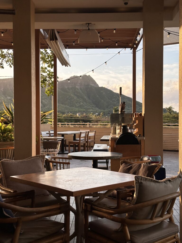 a patio with tables and chairs and a mountain in the background
