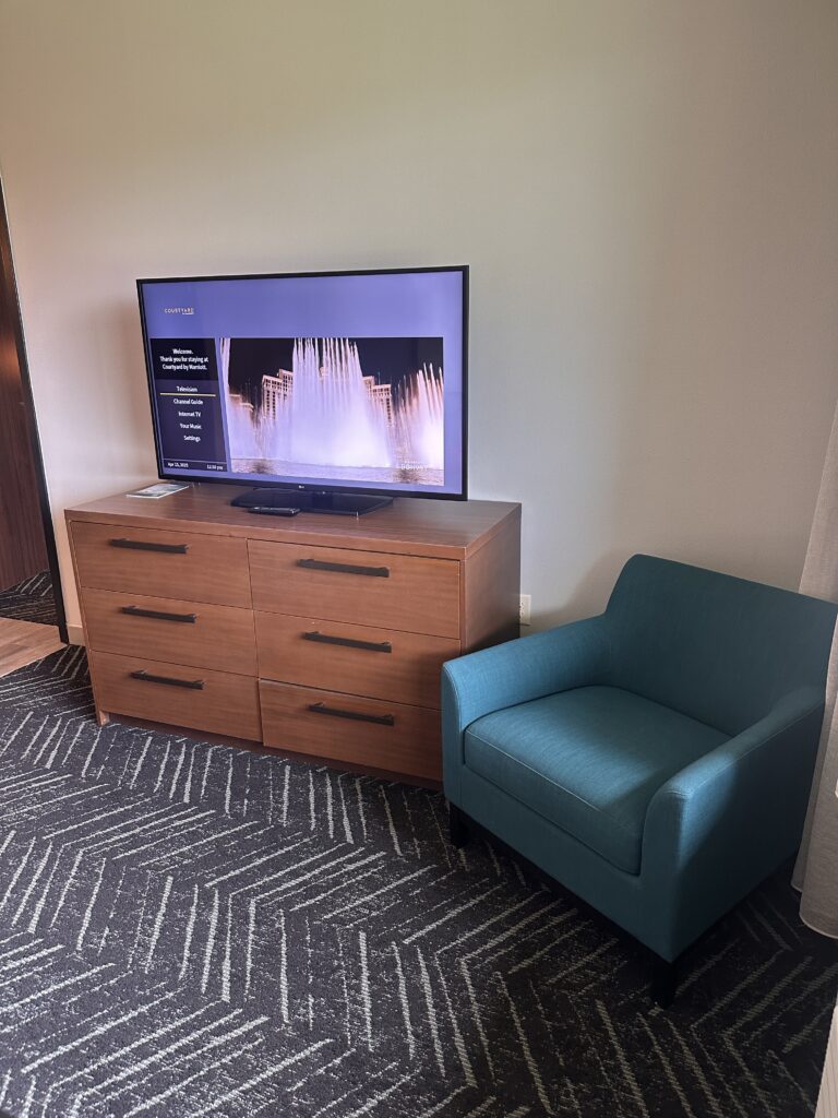 a tv on a dresser next to a chair