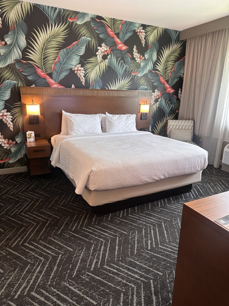 a bed with a headboard and lamps in a room with a floral wallpaper