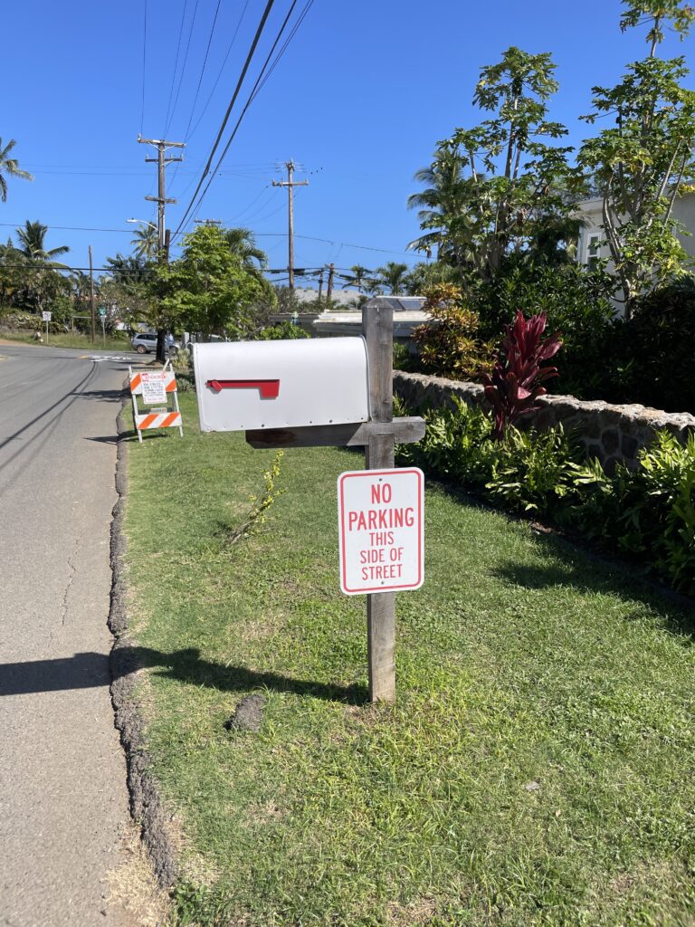 a white mailbox on a wooden post next to a road
