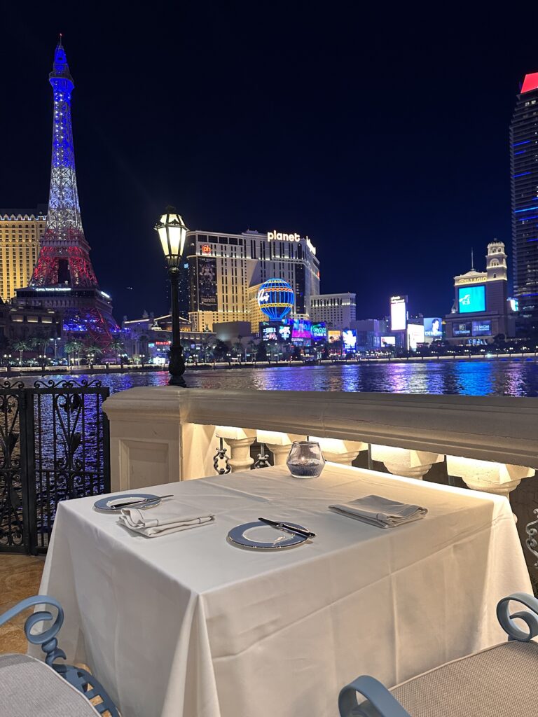 a table with plates and plates on it by a body of water with a tower in the background
